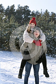 Happy loving couple is having fun in winter outdoors. Guy rolls girl on his back