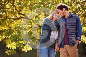 Happy Loving Couple Holding Hands Walking In Autumn Park Together