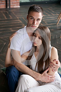 Happy loving couple hugs while sitting on floor at home, young man hugs girl