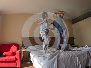 Happy loving couple jumping and having fun in bed