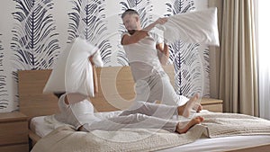 Happy loving couple jumping and having fun in bed