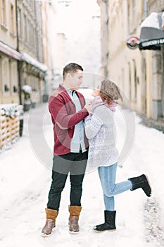 Happy loving couple kisses, enjoying Christmas or New year Holidays outdoor, walking on city streets