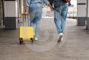 Happy loving couple with luggage and backpack walking along railway platform as they are ready to travel on holiday. Man and woman