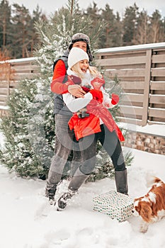 Happy loving couple is playing with dog on snowy day, winter holiday, inner child