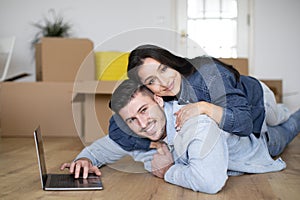 Happy Loving Couple Relaxing With Laptop After Moving Home