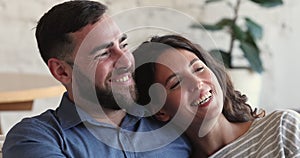 Happy loving couple relaxing on sofa smile looking at camera