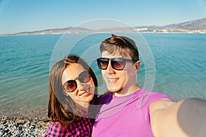 Happy loving couple taking self-portrait on beach