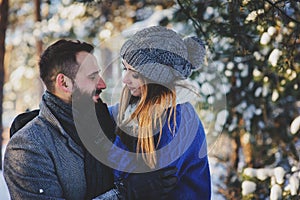 Happy loving couple walking in snowy winter forest, spending christmas vacation together.