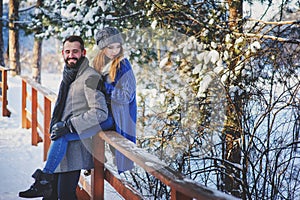 Happy loving couple walking in snowy winter forest, spending christmas vacation together.