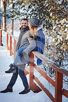 Happy loving couple walking in snowy winter forest, spending christmas vacation together.