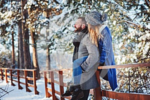 Happy loving couple walking in snowy winter forest, spending christmas vacation together.