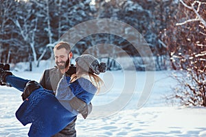 Happy loving couple walking in snowy winter forest, spending christmas vacation together.