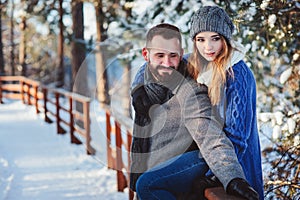 Happy loving couple walking in snowy winter forest, spending christmas vacation together.