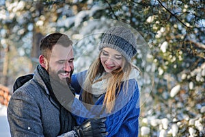 Happy loving couple walking in snowy winter forest, spending christmas vacation together.