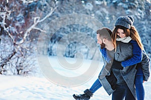 Happy loving couple walking in snowy winter forest, spending christmas vacation together. Outdoor seasonal activities