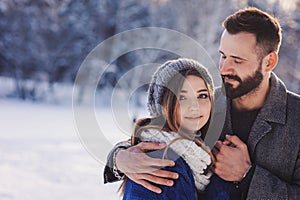 Happy loving couple walking in snowy winter forest, spending christmas vacation together. Outdoor seasonal activities
