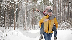 Happy loving couple walking in snowy winter forest, spending christmas vacation together. Outdoor seasonal activities