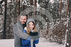 Happy loving couple walking in snowy winter forest, spending christmas vacation together. Outdoor seasonal activities.