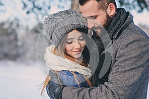 Happy loving couple walking in snowy winter forest, spending christmas vacation together. Outdoor seasonal activities.