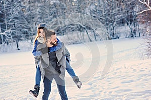 Happy loving couple walking in snowy winter forest, spending christmas vacation together. Outdoor seasonal activities.