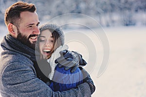 Happy loving couple walking in snowy winter forest, spending christmas vacation together. Outdoor seasonal activities.