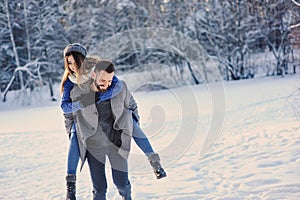 Happy loving couple walking in snowy winter forest, spending christmas vacation together. Outdoor seasonal activities.