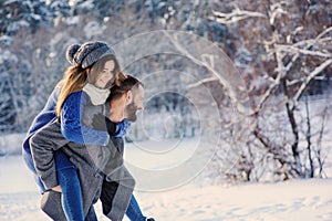 Happy loving couple walking in snowy winter forest, spending christmas vacation together. Outdoor seasonal activities.