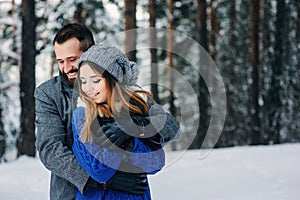 Happy loving couple walking in snowy winter forest, spending christmas vacation together. Outdoor seasonal activities