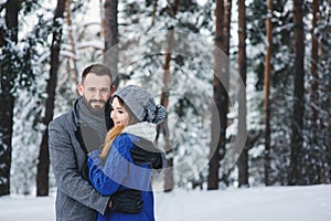 Happy loving couple walking in snowy winter forest, spending christmas vacation together. Outdoor seasonal activities