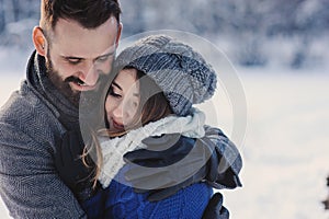 Happy loving couple walking in snowy winter forest, spending christmas vacation together. Outdoor seasonal activities