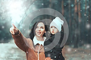 Happy loving family! Beautiful mother and child girl having fun, playing and laughing on snowy winter walk in nature. Frost winter