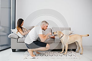 Happy Loving Family Concept. Portrait of beautiful couple with dog sitting on the floor in modern apartment