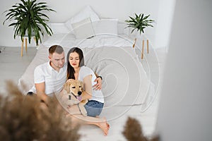 Happy Loving Family Concept. Portrait of beautiful couple with dog sitting on the floor in modern apartment