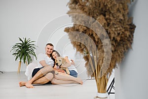 Happy Loving Family Concept. Portrait of beautiful couple with dog sitting on the floor in modern apartment