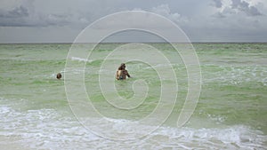 Happy loving family of father, mother and son having fun in sea water on the beach- Summer, travel, vacation and family