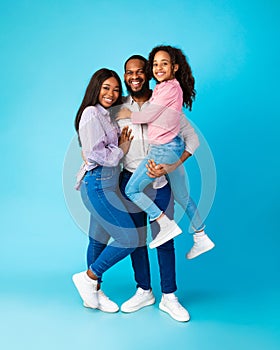 African American man and woman embracing smiling daughter