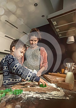 Happy loving family in the kitchen before Christmas. Mother and child preparing the dough, bake ginger cookies