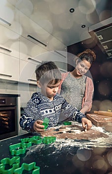 Happy loving family in the kitchen before Christmas. Mother and child preparing the dough, bake ginger cookies