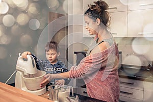 Happy loving family in the kitchen before Christmas. Mother and child preparing the dough, bake ginger cookies