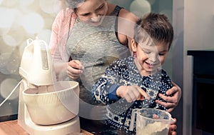 Happy loving family in the kitchen before Christmas. Mother and child preparing the dough, bake ginger cookies