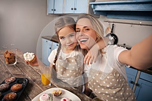 Happy loving family in the kitchen. Mother and child daughter girl are eating cookies they have made and having fun in