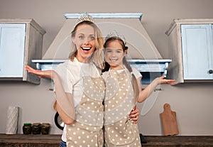 Happy loving family in the kitchen. Mother and child daughter girl are having fun wearing crowns