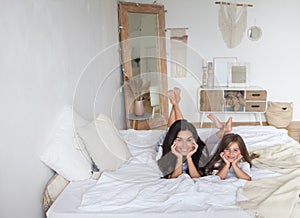 Happy loving family lying relaxing and enjoying in bedroom together. Mother and her cute preschool daughter child girl in pajamas