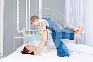 A happy, loving family. Mom and baby son play at home on the bed, have fun and laugh