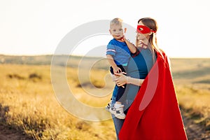 Happy loving family. Mom and her son are playing outdoors. Mom and her child in Superhero costumes. Mother`s day concept