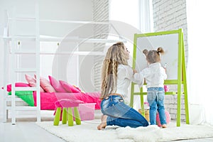 Happy loving family. Mother and daughter in the children`s room. Cute little girl is playing with a woman.