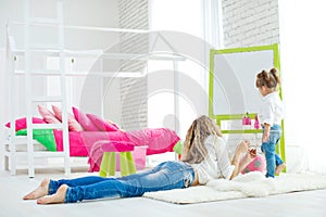 Happy loving family. Mother and daughter in the children`s room. Cute little girl is playing with a woman.