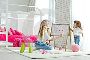 Happy loving family. Mother and daughter in the children`s room. Cute little girl is playing with a woman.