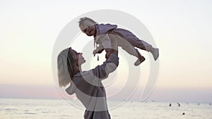 Happy loving family mother and daughter have fun on the beach at sunrise. Mom plays with her baby. vacation, family