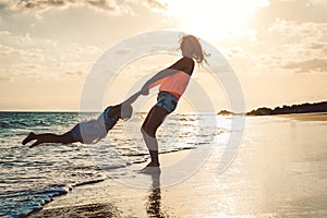 Happy loving family mother and daughter having fun on the beach at sunset - Mum playing with her kid next sea in holidays